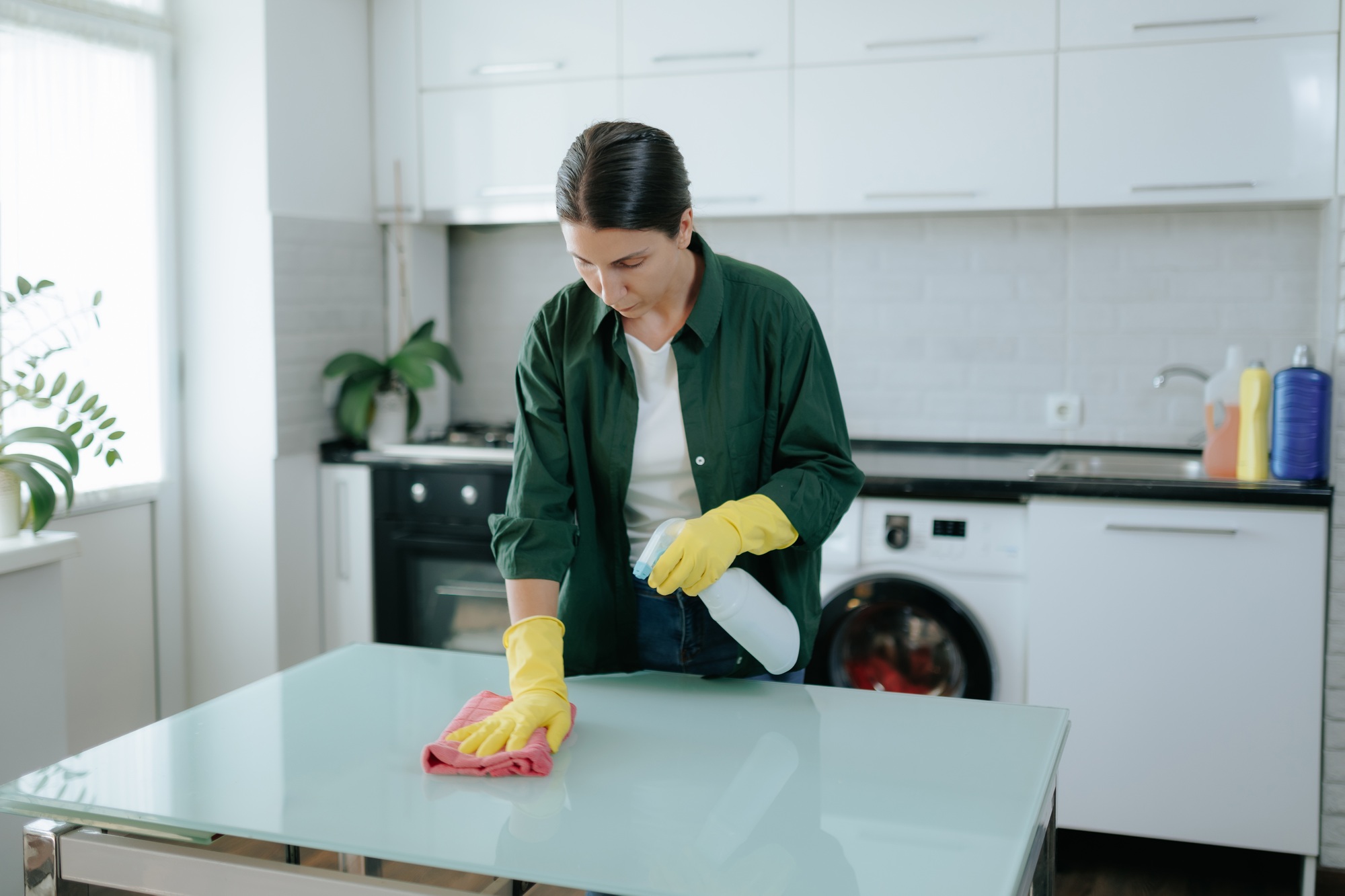 Housewife with Yellow Gloves Cleaning Kitchen Table at Home